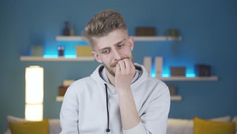 young man biting his nails is worried and needs to think in a panic.