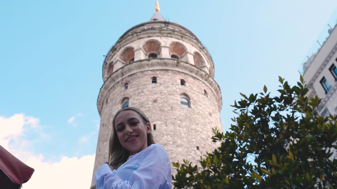 Cámara lenta: Atractiva joven y hermosa chica posa frente a la Torre de Gálata, un popular monumento en Estambul, Turquía.