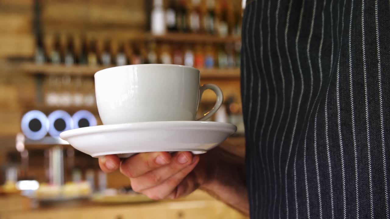 Cameriere con una tazza di caffè in mano al bar 4k
