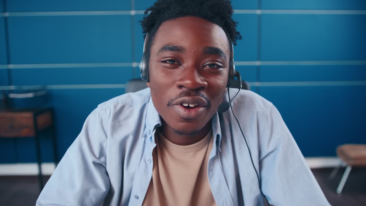 헤드을 착용한 행복한 아프리카계 미국인 남자가 웹캠을 통해 '안하세요'라고 말합니다.