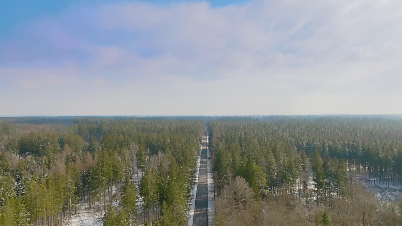 자동차가 카메라 방향을 따라 운전하는 동안 겨울 숲 위로 드론 비행