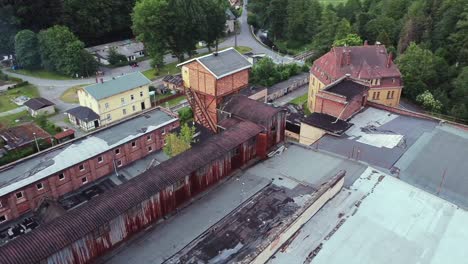 top view of a drone circling around a giant old lost place factory in the woods with a demolished roof in the middle of nowhere