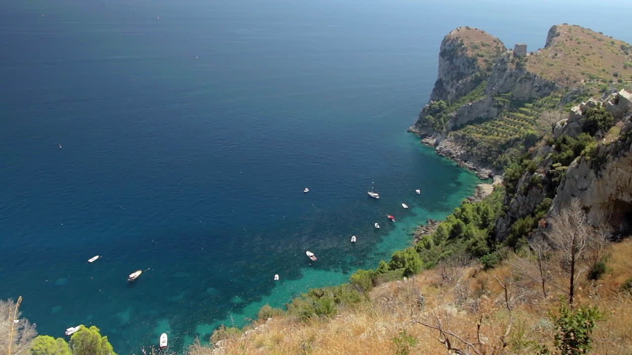 Rocky Coastline And Turquoise Sea Surface With Boats Moored In Amalfi Coast