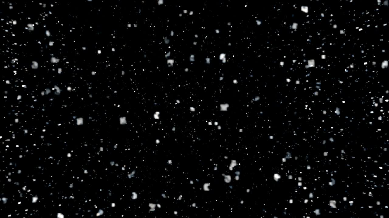Several snow particles falling down over a black background