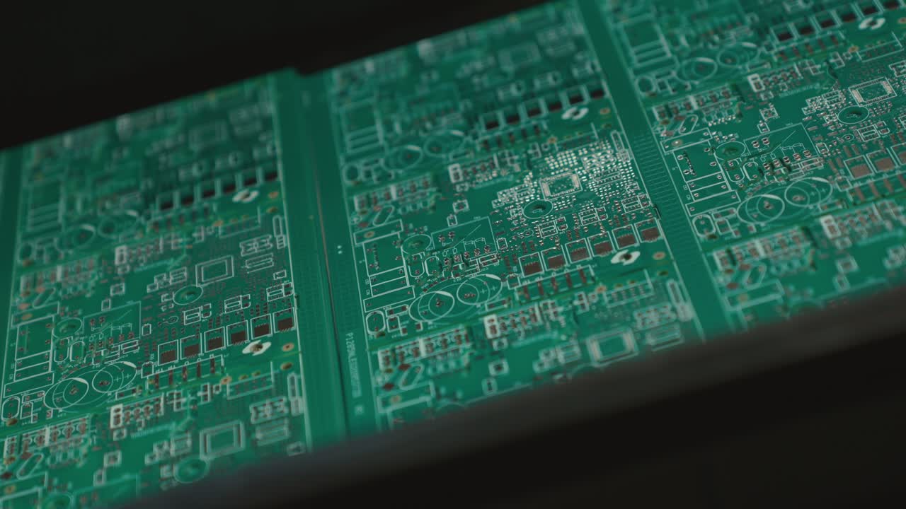 Slow motion close-up of green circuit boards in assembly