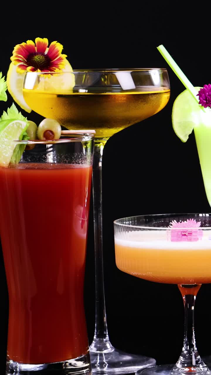 A vibrant display of various cocktails in elegant glassware against a black background, highlighting their colors and garnishes