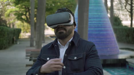 concentrated bearded man using vr glasses on street
