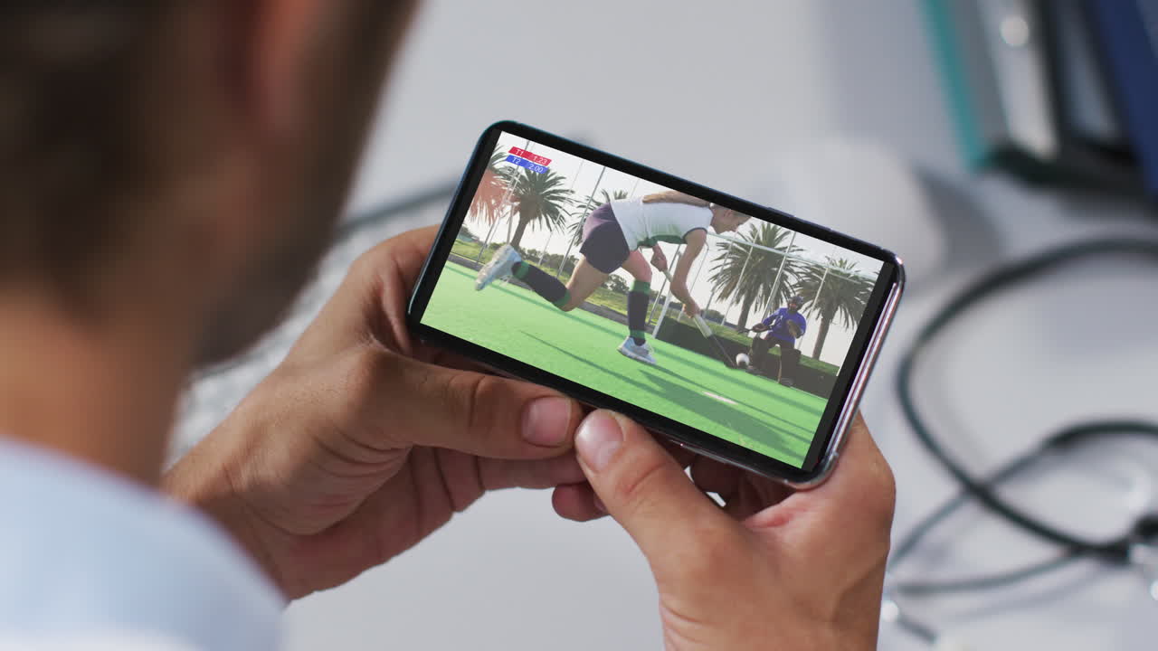 Medico uomo che guarda una partita di hockey sullo smartphone