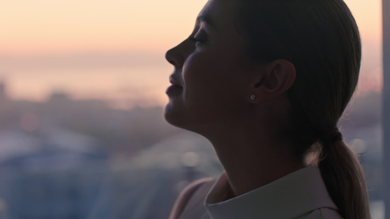 hermosa mujer de negocios mirando por la ventana contemplando un estilo de vida exitoso planeando adelante disfrutando de la vista de la ciudad desde el ático al atardecer