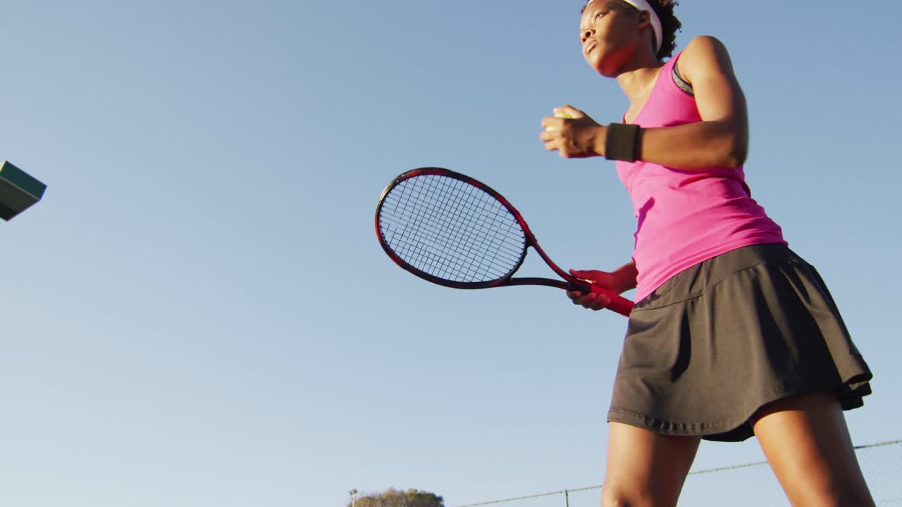라켓을 들고 공을 치는 아프리카계 미국인 여성 테니스 선수의 낮은 각도의 비디오