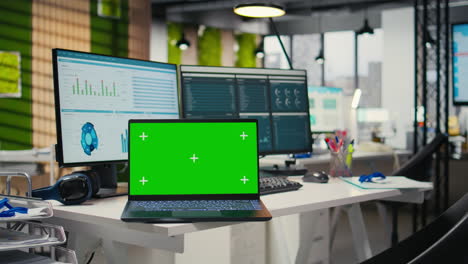 empty modern office space presents dual monitors and green screen on laptop