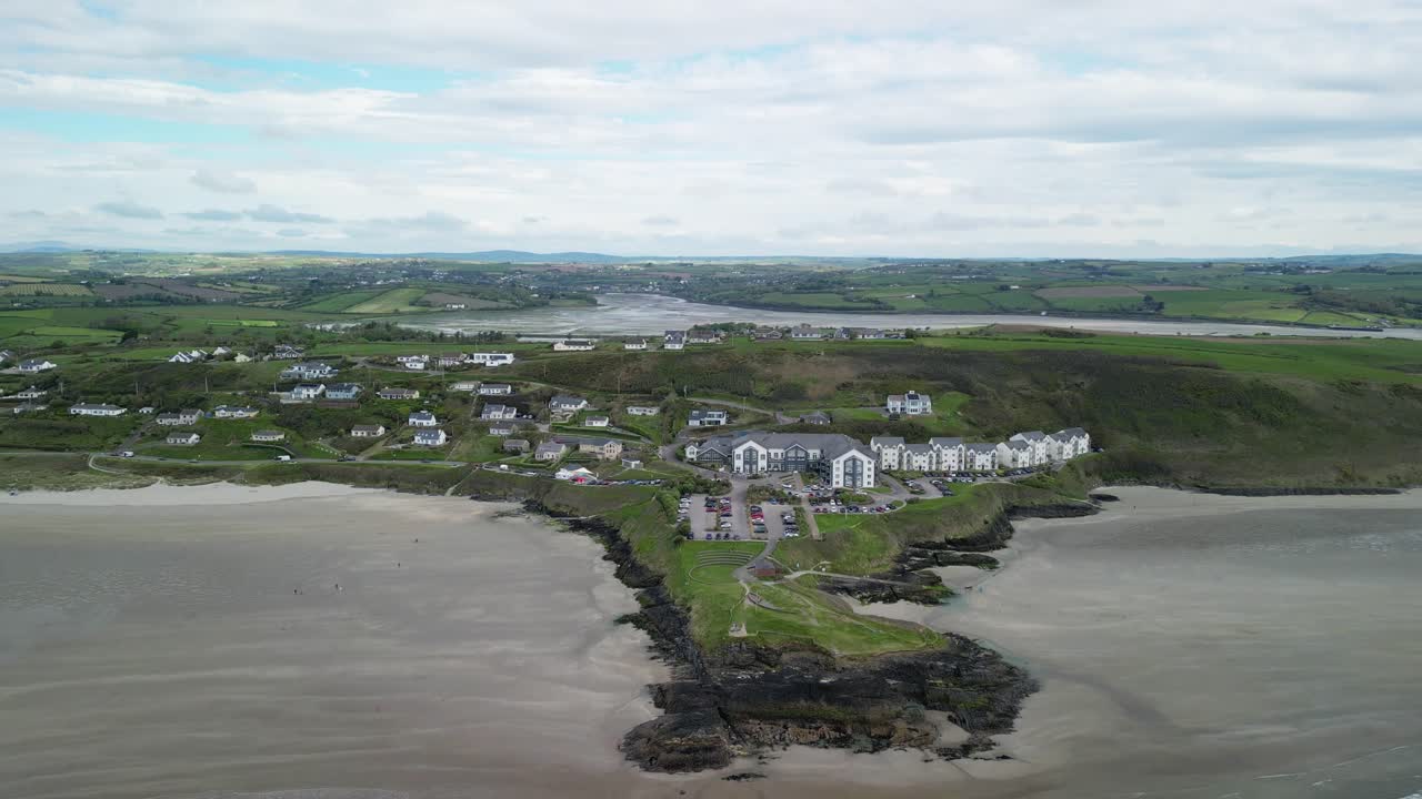 Aerial drone footage over coastal area, Inchidoney sandy beach, cliffs, and village. Ireland, Clonakilty