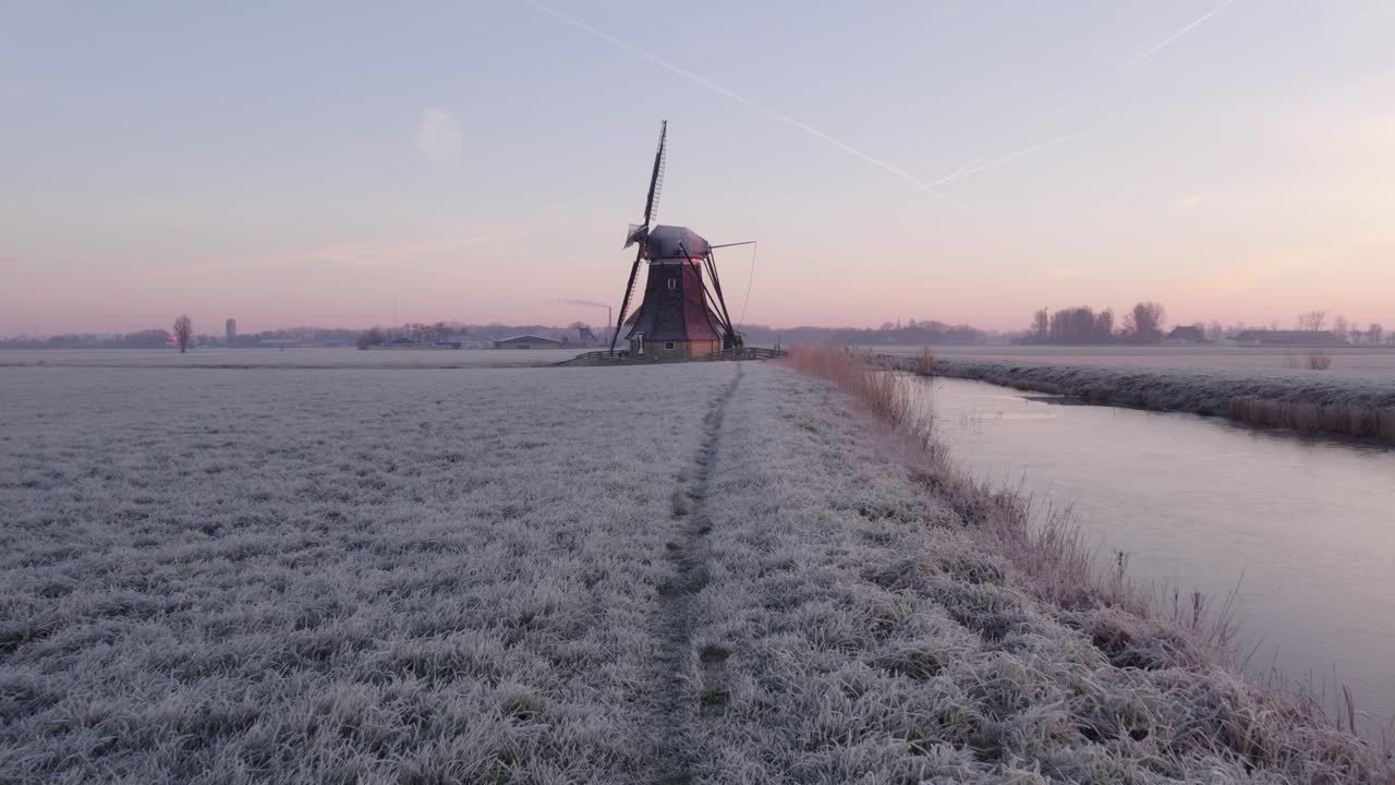 추운 겨울 아침, 공중에서 얼어붙은 잔디와 함께 네덜란드 풍차에서 낮은 비행