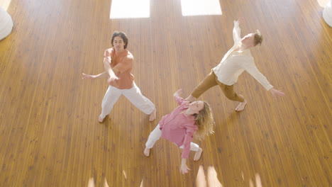 top view of multiethnic group of contemporary dancers dancing in the middle of studio and looking at camera