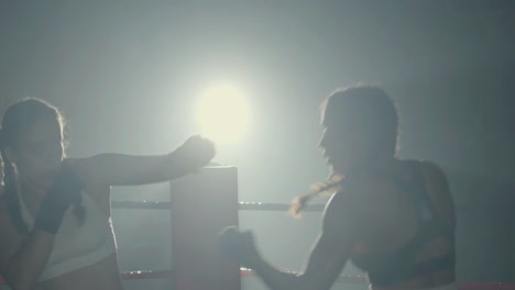 jóvenes boxeadoras peleando mientras entrenan juntas en un gimnasio de boxeo en la oscuridad