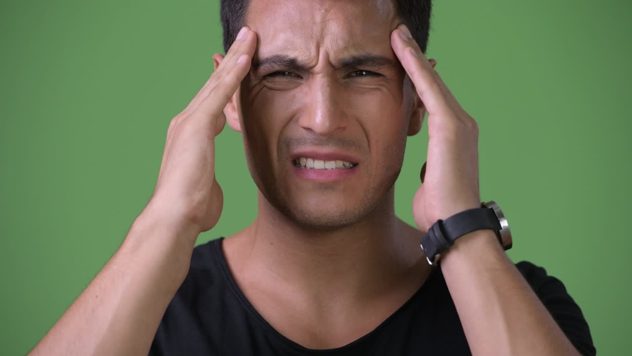 joven y guapo hombre hispano contra un fondo verde