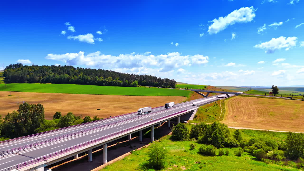 Lorries and cars run by the freeways in the countryside. Aerial perspective on the highways along the rural area.