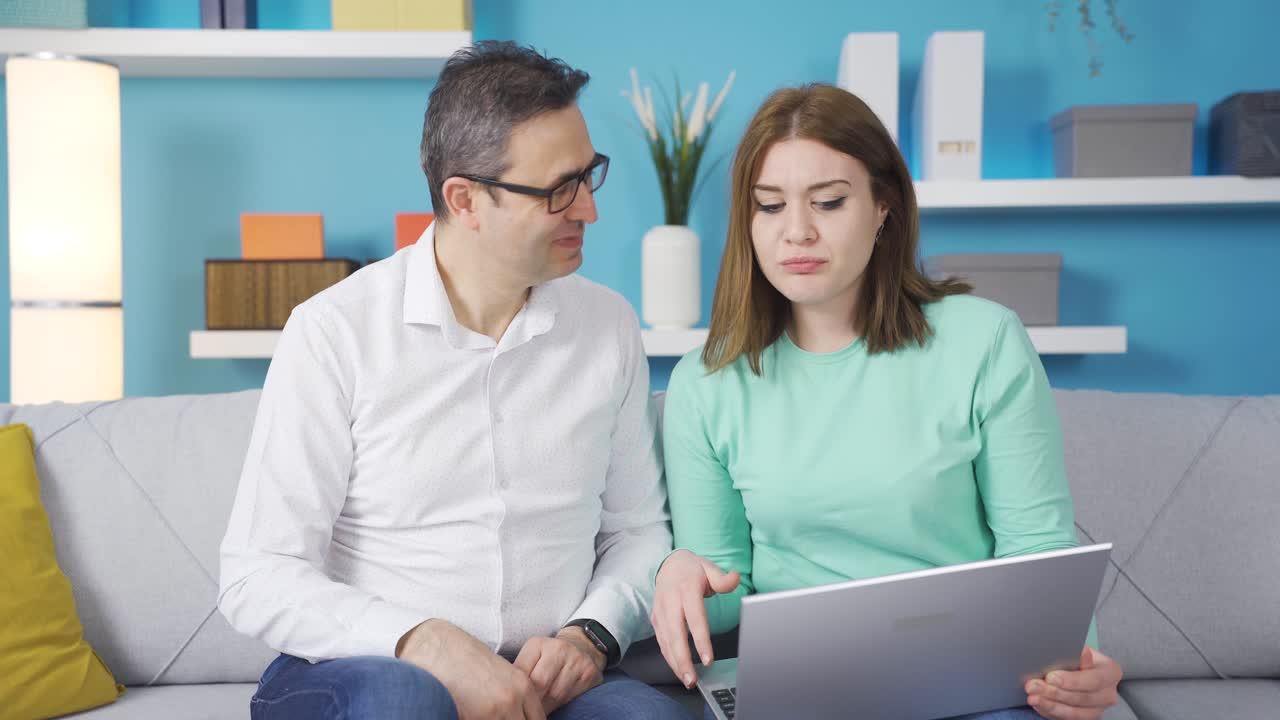 una niña le muestra el portátil a su padre. explica su uso. uso de tecnología.