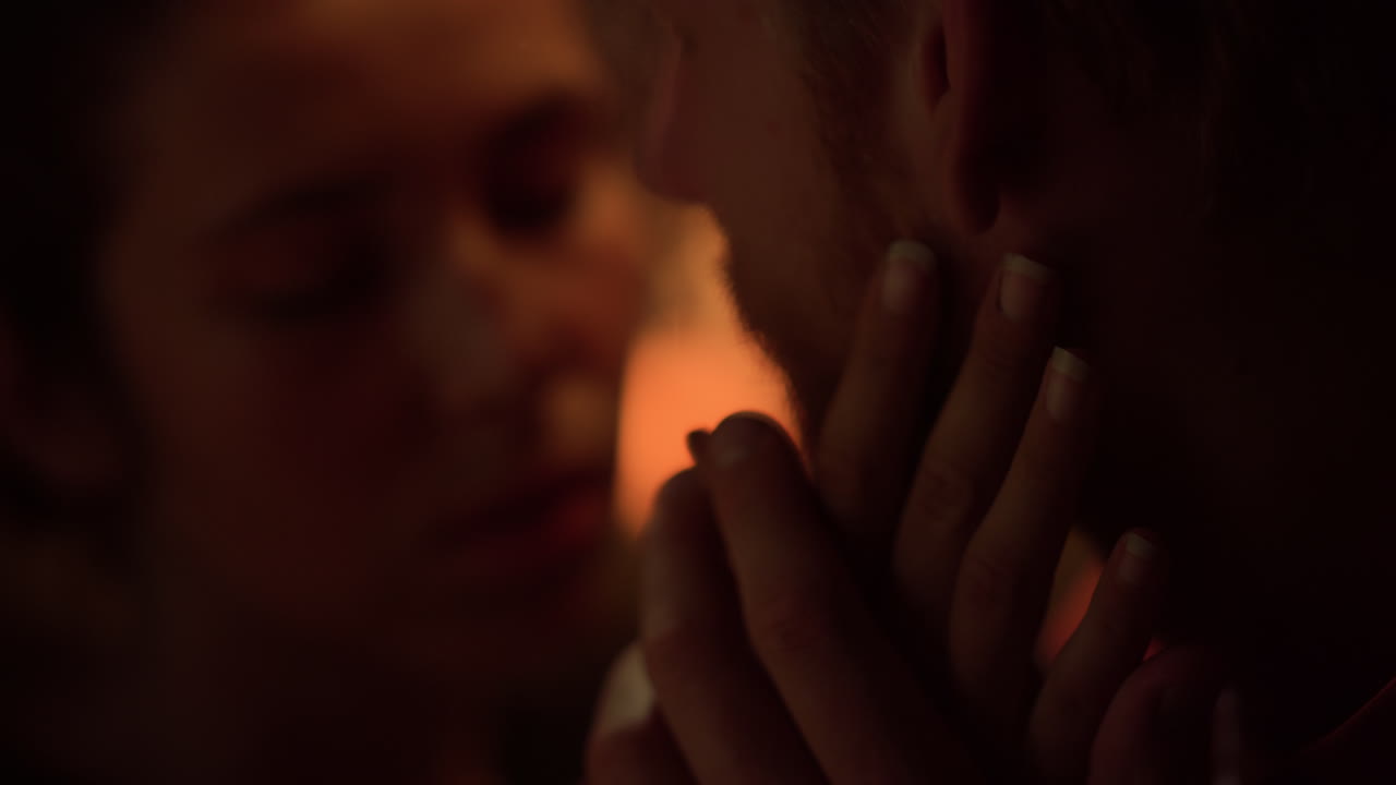 en primer plano, los amantes románticos se tocan las caras por la noche. una pareja amorosa se da la mano en el interior.