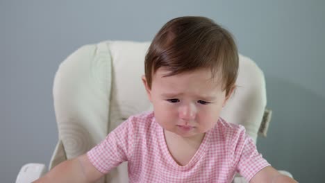 Cute-Baby-Girl-Getting-A-Little-Upset-While-Sitting-In-High-Chair