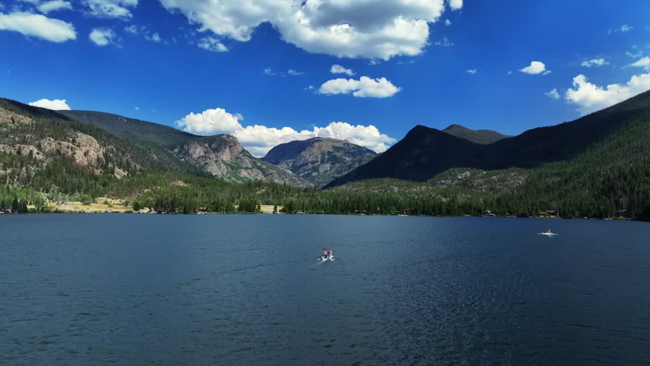 Summer Grand Lake Granby pontoon boating sailboat aerial drone Colorado Rocky Mountains National Park entrance sunny morning daytime clouds lake homes blue sky sunny clouds forward upwards motion