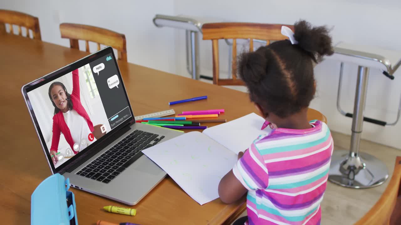 Schoolgirl using laptop for online lesson at home, with her school friend and web chat on screen