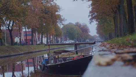 canal de agua y barco en el pueblo de los países bajos holanda en el otoño otoño con casas, árboles y hojas al lado de la calle tranquila camino