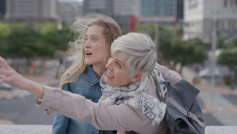 schöne glückliche frauen lachen zusammen, umarmen sich, aufgeregte mutter zeigt auf, dass ihre tochter den sommerurlaub in der stadt in langsamer bewegung genießt.