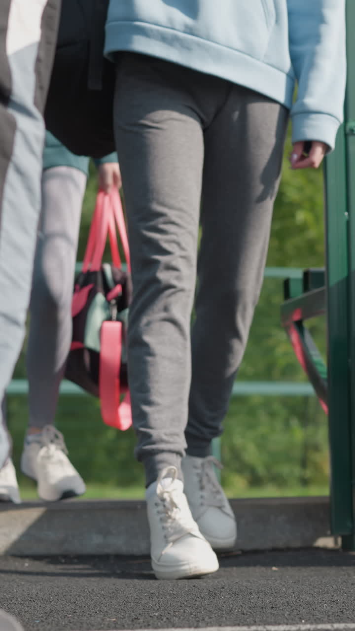 스니커에서 발을 잡는 낮은 각도 뷰, 조거에서 사람들이 스포츠 코트에 걸어, 녹색 게이트와 주머니와 의자, 활동에 준비