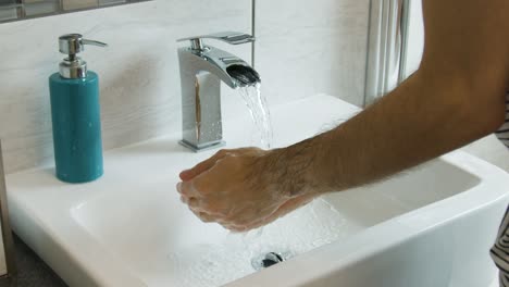 male rinsing soap off of hands and arms in a bathroom sink in super slow motion