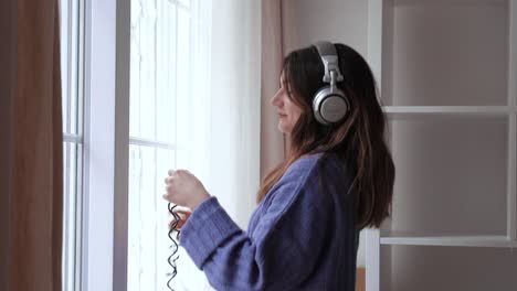 beautiful young girl is dancing while listening to music at her home