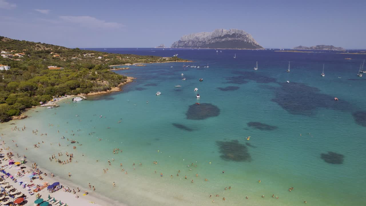 Vista aérea de una impresionante playa turquesa con barcos y una isla en el mar Mediterráneo.
