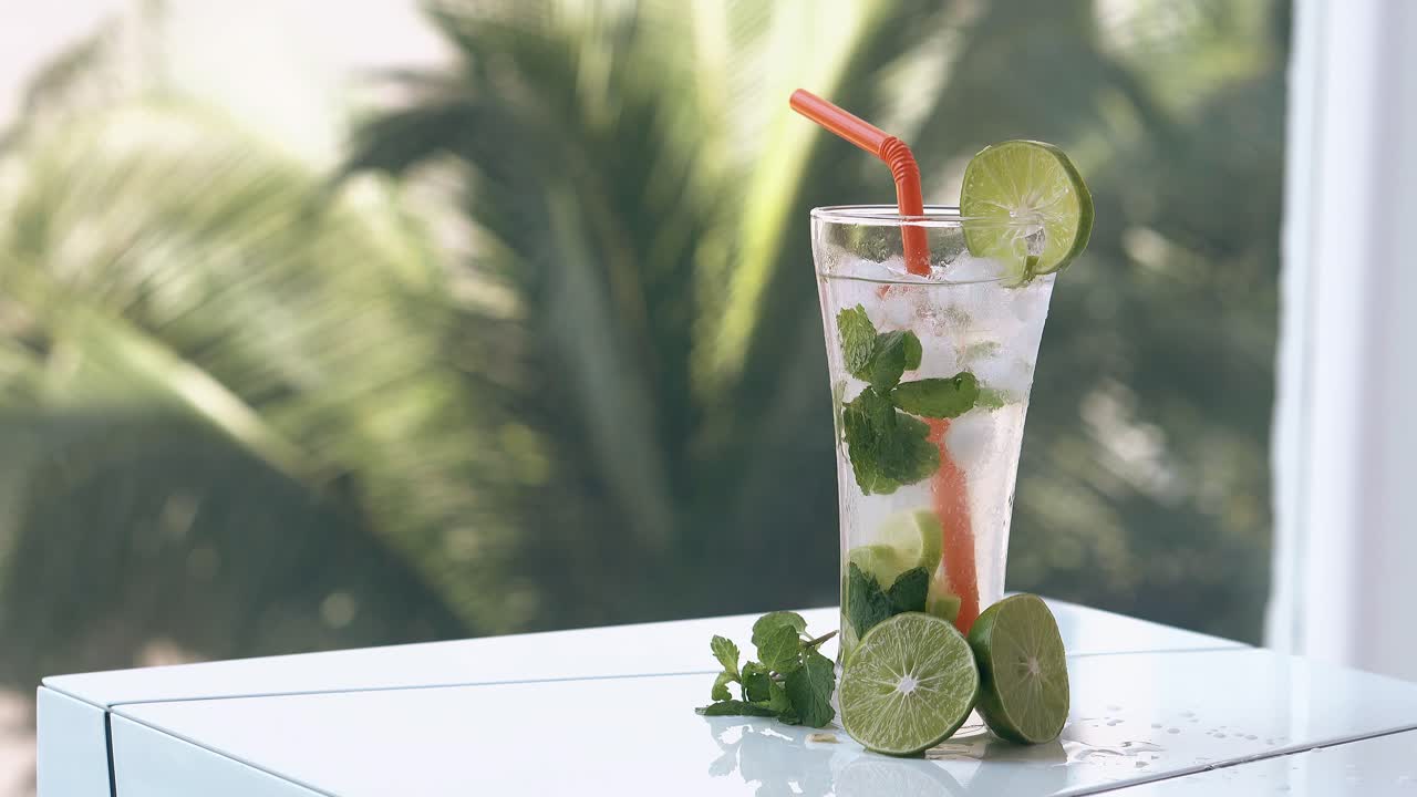 녹색 종려나무 잎은 음료와 함께 테이블 뒤에서 바람에 움직입니다