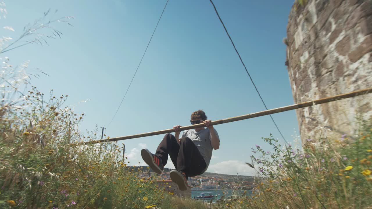 un joven en forma haciendo ejercicios de musculación y salsas en la calle usando un bar al aire libre
