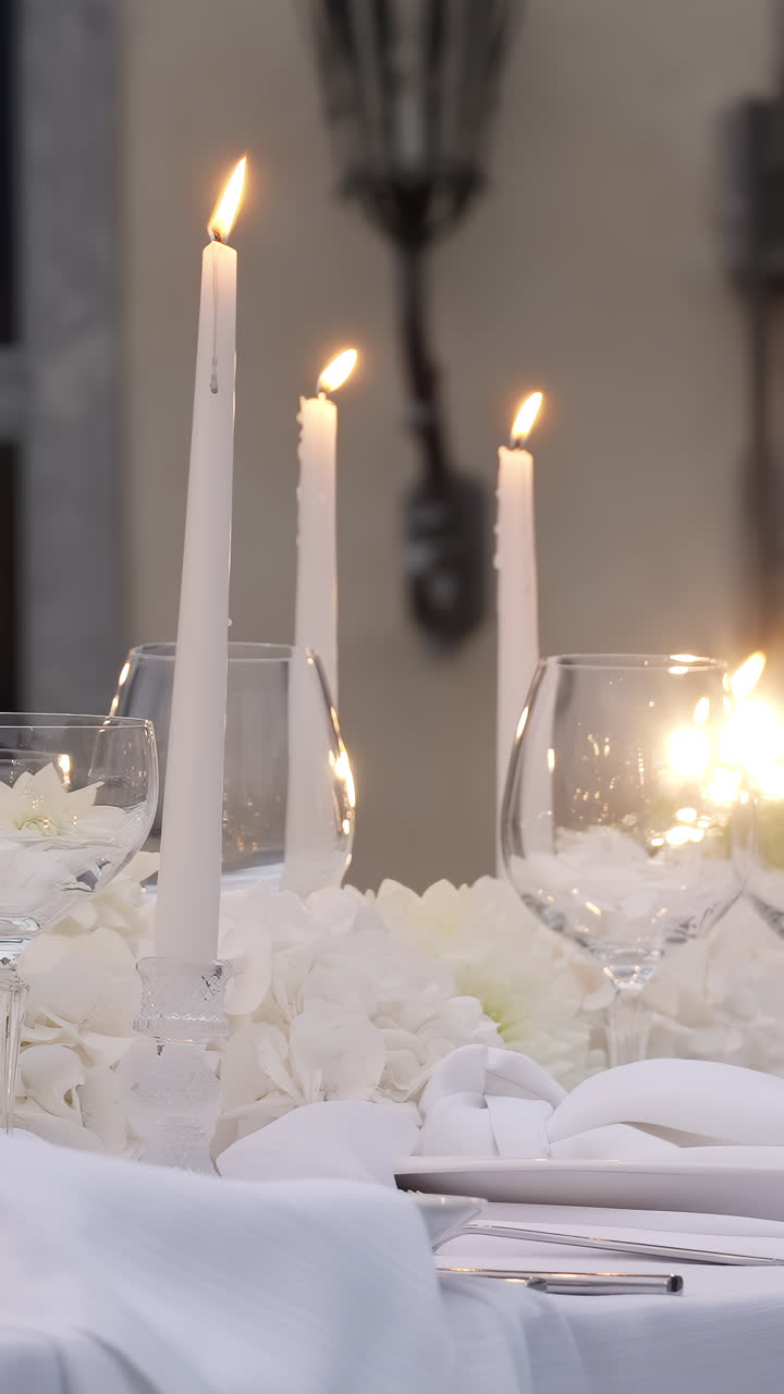 Elegante apparecchiatura della tavola con candele accese e fiori bianchi