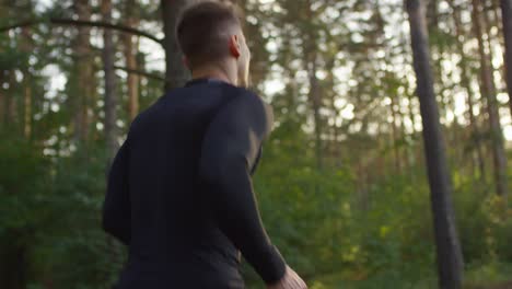 vista trasera de un hombre deportivo corriendo en el bosque