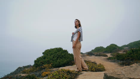 Carefree-girl-look-ocean-resting-on-rocky-cliff.-Vertical-tourist-enjoy-vacation