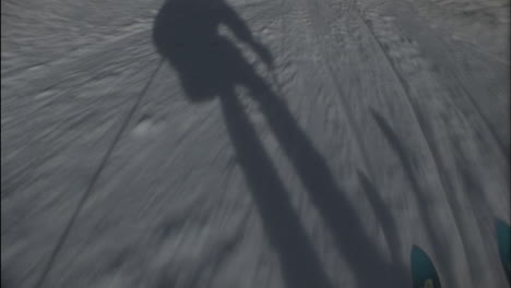 a skier's shadow precedes him down the hill