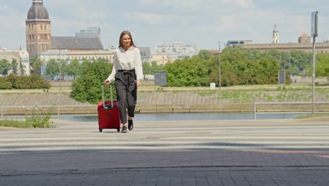 female businesswoman crosses pedestrian crossing while pulling suitcase, riga