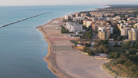 toma aérea a 30 fps de una playa de arena con paraguas, típica costa adriática