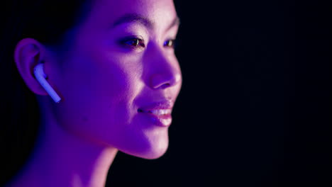 woman with wireless earbuds in profile view under purple light