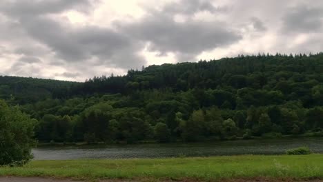 Fast-moving-landscape-view-while-driving-during-overcast-summer-day,-Germany