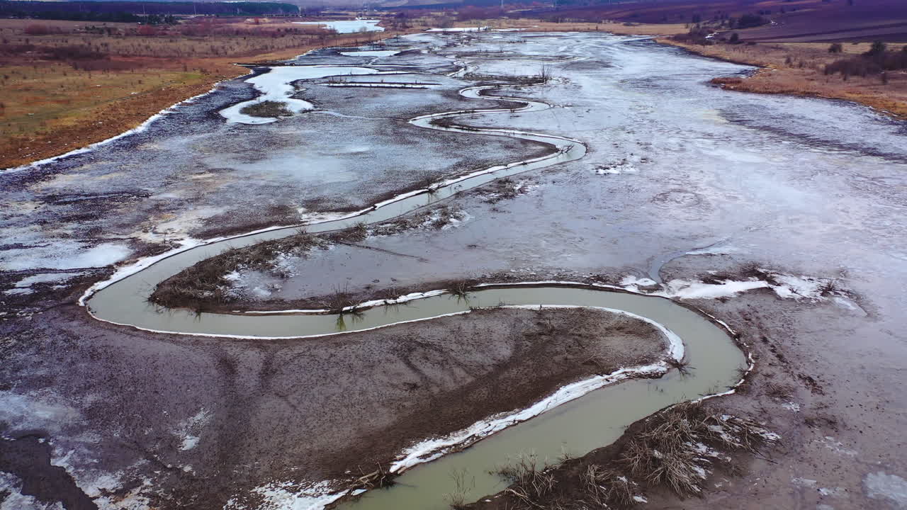 Tortuous river in muddy place. Ecological problems with water. Global warming. Narrow stream from dried river. Nature in danger. View from above.