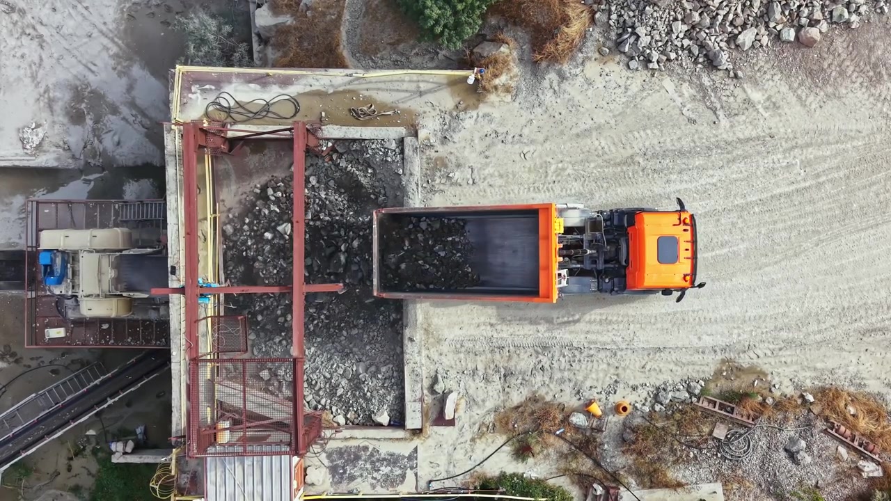 Truck delivering stone at granite quarry site in daytime