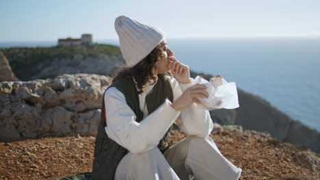 Chica-Excursionista-Comiendo-Comida-En-El-Acantilado-Del-Océano-Vertical.-Sereno-Desayuno-De-Viaje-En-El-Océano