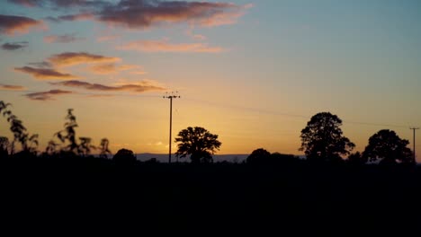 atardecer rural dorado con línea telefónica y poste de servicios públicos