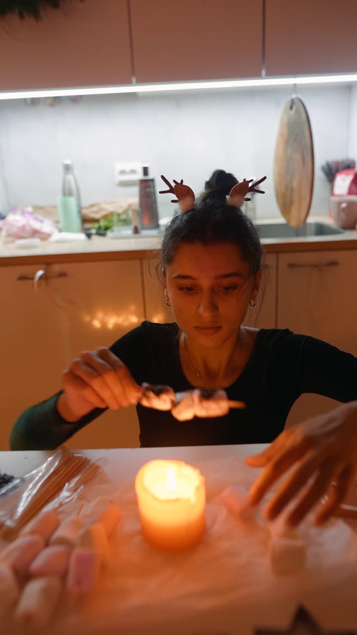 Woman roasting marshmallows over candle in kitchen