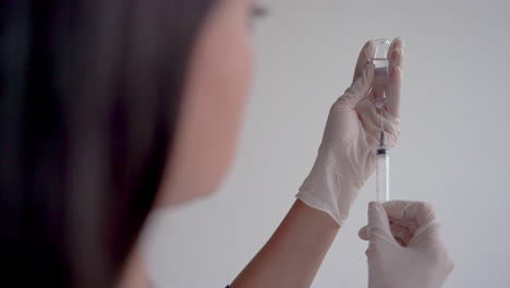 close up of a doctor filling a syringe with a vaccine