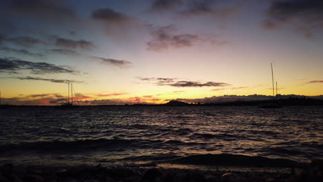 escena oscura durante una hermosa puesta de sol que refleja la luz colorida en las olas, slowmo