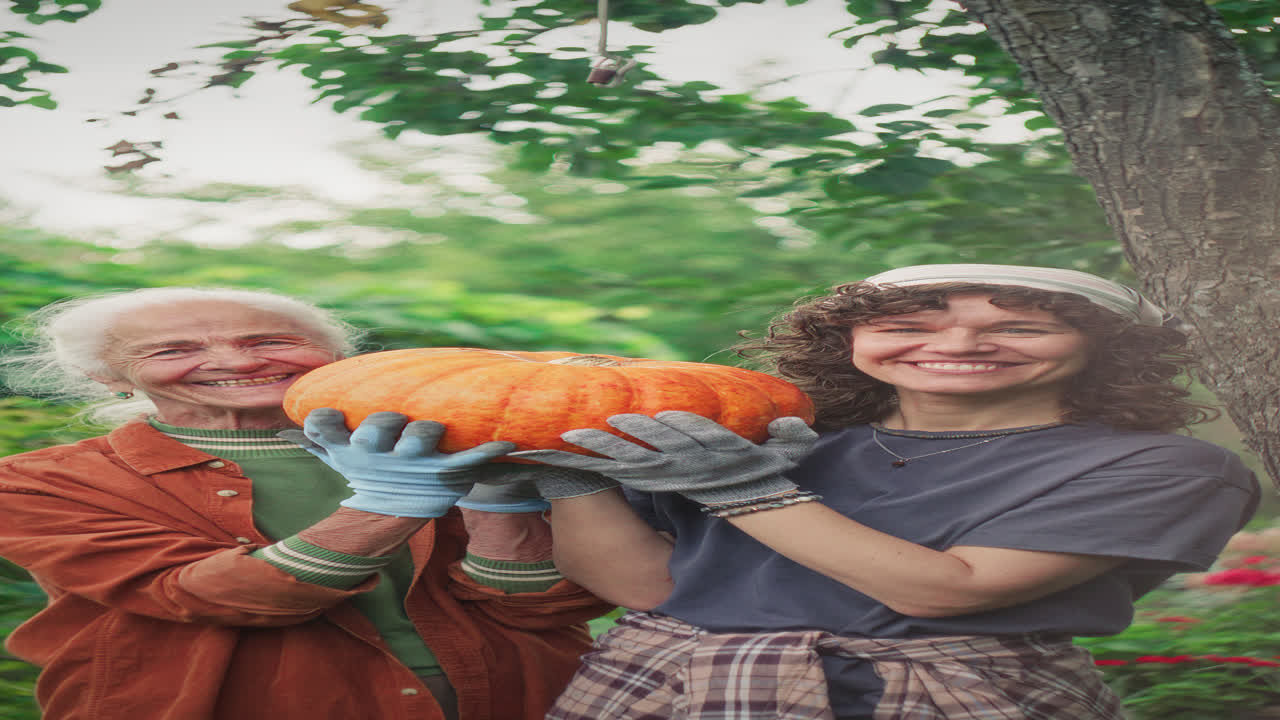 Portrait of Smiling Elderly Woman and Granddaughter Holding Harvested Pumpkin